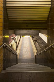 View looking down main stair of St George’s Cross subway station to platform with train waiting in station