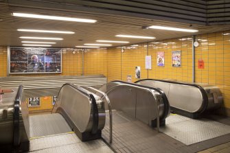 View looking into the double-height stair hall from the top of the escalators within the concourse of St Geroge’s Cross subway station