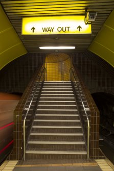 View taken from platform level of main stair linking platform and concourse levels of West Street subway station, with train arriving in station