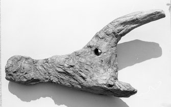 An oak claw thole from a clinker-built vessel, apparently re-used in a building in a context dating from the second half of the 12th century. These devices were mounted on top of the gunwale as fulcrums against which the oars were pivoted. The oars were restrained on the backstroke by a rope or leather thong grommet for which the hole was provided. These items are a common feature of early Northern-European boats and have survived in Scandinavia into modern times. One was recognised as a sand-impression on the 7th-century AD Sutton Hoo ship, while others have been identified on the 4th-century AD Nydam ship, and on the small faering found with the 9th-century AD Gokstad ship. (Cat No 84/A6085)