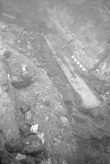 Part of the bottom of the main gulley from which an overburden of shingle some 2m deep has been removed. The very bottom is entirely filled with ferrous concretion within which, by the 1-foot scale, a partly-sectioned iron gun is revealed (1977).