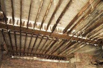 Interior. View looking up to roof structure, showing main structural beams, with concrete roof above and timbers of suspended ceiling of interior.