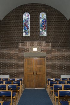 Interior. East entrance with stained glass windows above, view from west