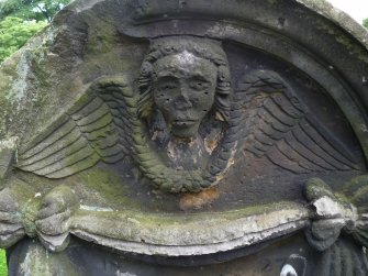 Detail of relief showing the head and wings of an angel, weathered. Saint Cuthbert's Cemetery, Edinburgh.