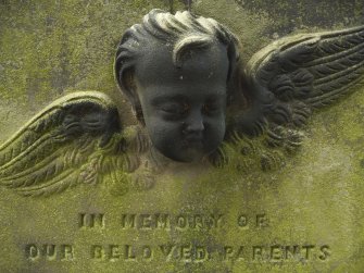 Detail of headstone relief of the head and wings of an angel, 'in loving memory of our parents', Canongate Kirk Cemetery, Edinburgh.