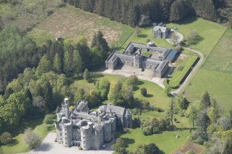 General oblique aerial view of Cluny Castle with adjacent stable blocks, looking to the NW.