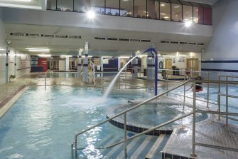 Interior. View looking north across the swimming pool hall, with the viewing area of the main concourse to upper level.