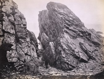 Wide view of rock formations, including figure, on the beach of Kilchattan, Colonsay.
Titled: '138. Behind Kilchattan, Colonsay.'
PHOTOGRAPH ALBUM NO 186: J B MACKENZIE ALBUMS vol.1