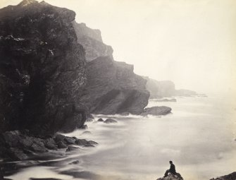 Wide view of rock formations and surrounding sea, including figure, on the beach of Kilchattan, Colonsay.
Titled: '139. Behind Kilchattan, Colonsay.'
PHOTOGRAPH ALBUM NO 186: J B MACKENZIE ALBUMS vol.1