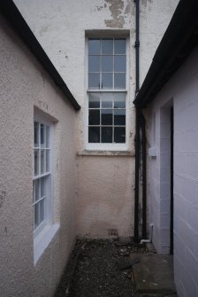 Exterior view of staircase window showing upper floor level.  '8 over 8' window to original cottage to left, kitchen extension to right.