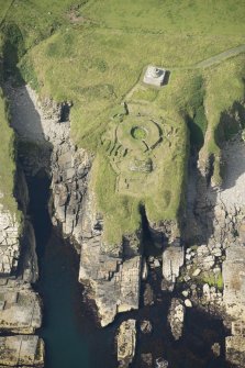 Oblique aerial view of Nybster Broch and Nybster Commemorative Monument, looking SW.