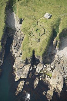 Oblique aerial view of Nybster Broch and Nybster Commemorative Monument, looking WSW.