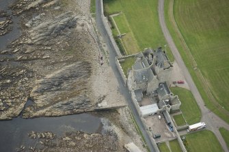 Oblique aerial view of Ackergill Tower and walled gardens, looking SE.