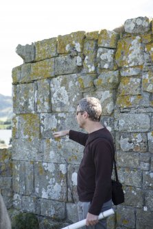 Piers Dixon explaining features of outside of west wall of priory church