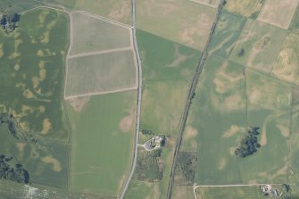 Oblique aerial view of the cropmarks of the enclosures, round house and pits, looking SW.