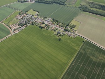 Oblique aerial view of Athelstaneford village with the cropmarks of possible buildings and road adjacent, looking SSE.