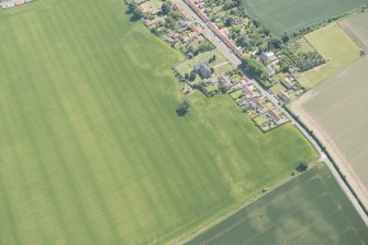 Oblique aerial view of Athelstaneford with the cropmarks of possible buildings and road adjacent, looking SE.