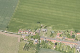 Oblique aerial view of Athelstaneford village with the cropmarks of possible buildings and road adjacent, looking N.