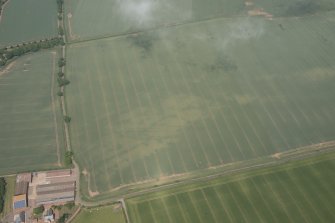 Oblique aerial view of the cropmarks of the trackway, quarries and linear ditches, and adajcent farm buildings at Wester Broomhouse, looking NNW.