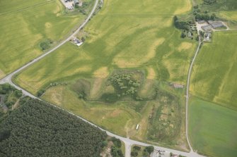 Oblique aerial view of the cropmarks of the fort, linear feature, enclosure, and pits at Gilchrist, looking E.