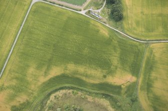 Oblique aerial view of the cropmarks of the enclosure, possible roundhouse and pits, looking ESE.