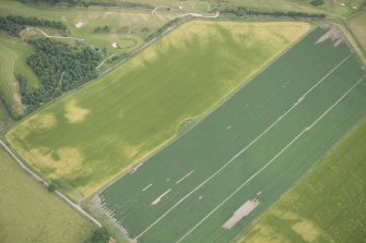 Oblique aerial view of the cropmarks of the enclosure, possible sunken floored buildings and pits, looking E.