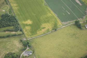 Oblique aerial view of the cropmarks of the enclosure, possible sunken floored building and pits, looking SE.