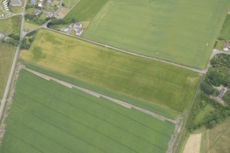 Oblique aerial view of the cropmarks of the vallum at Portmahomack, looking NNE.