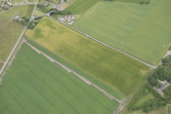 Oblique aerial view of the cropmarks of the vallum at Portmahomack, looking NNE.