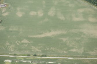 Oblique aerial view of the cropmarks of the possible round house, rig and pits at Drumore, looking NW.