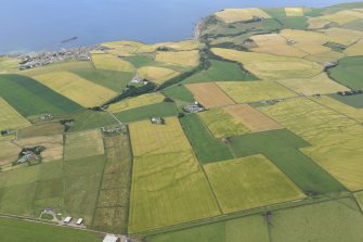 General oblique aerial view centred on the geological cropmarks at Braco Den with Crovie and Gardenstown beyond, looking NNW.