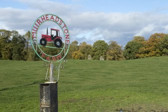 View of  'Muirheadstone Farm' sign with pair of standing stones in background