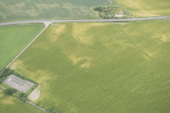 Oblique aerial view of the cropmarks of the settlement, ring ditch and pits, looking NNW.