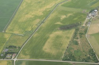 Oblique aerial view of the cropmarks of a possible sunken floored building and round house, looking WSW.