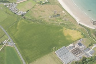 Oblique aerial view of the cropmarks of the ring ditch and the remains of the windmill at Sandend, looking NW.