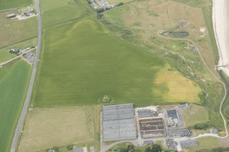 Oblique aerial view of the cropmarks of the ring ditch and the remains of the windmill at Sandend, looking WNW.