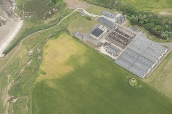 Oblique aerial view of the remains of the windmill and Glenglassaugh Distillery at Sandend, looking ENE.