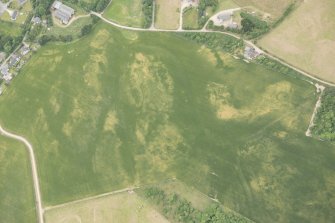 Oblique aerial view of the cropmarks of the ring ditch, possible building and pits, looking NW.