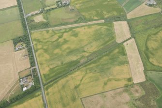 Oblique aerial view of the cropmarks of the possible round house, sunken floored building, field boundary, rig and pits, looking NNE.