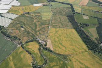 General oblique aerial view centred on the cropmarks of the enclosures, timber hall and unenclosed settlement, looking SSE.