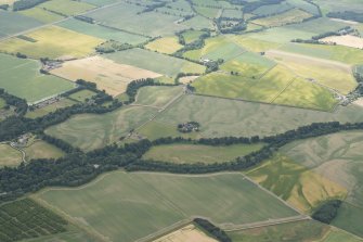 General oblique aerial view centred on the cropmarks of the unenclosed settlement, ring ditches, pits and rig with Stracathro Roman Fort and Temporary Camp adjacent at Smiddyhill, looking to the SSW.