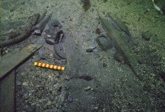 Material beneath the collapsed interior woodwork, including (centre right) a leather shoe, and moving left a wooden sheave, two pump-valves, and a length of served rope. Scale 15 centimetres. (Colin Martin)