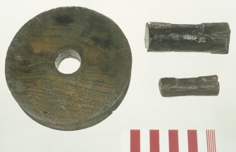 A wooden sheave or pulley wheel (DP97/A011) and two wooden pins (DP00/062 (top), 080). Note the wear on the pins. Scale 10 centimetres. (Colin Martin)
