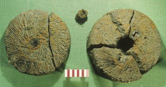 The upper (left) and lower stones of a hand-mill or quern (DP02/003). The grinding faces are shown. The small concretion is associated with the iron rotating mechanism. Scale 10 centimetres. (Colin Martin)