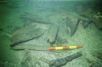 Inverted wooden gun-carriage (DP00/013) associated with Gun 8 (DP00/203) (right centre) during excavation. Scale 50 centimetres. (Colin Martin)