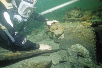 An archaeologist examines the inverted wooden gun-carriage (DP00/013) associated with Gun 8 (DP00/203) after excavation. (Colin Martin)