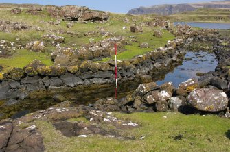 The upper canal from the edge of the northernmost naust. The 2-m pole marks a distinctive change in the stonework of the revetment on the far side of the canal. (Colin Martin)