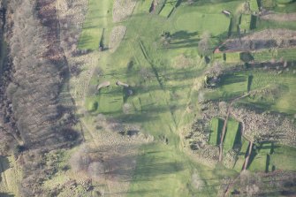 Oblique aerial view centred on part of the disused race course, the farmstead and the golf course, looking WNW.