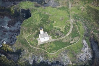 Oblique aerial view of Fidra lighthouse and cottage block, and metal wire running down cliff face, looking ESE.