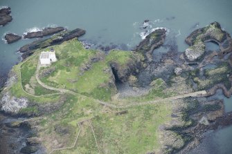 Oblique aerial view of Fidra lighthouse and cottage block, pier, and St Nicholas Church, looking NNE.